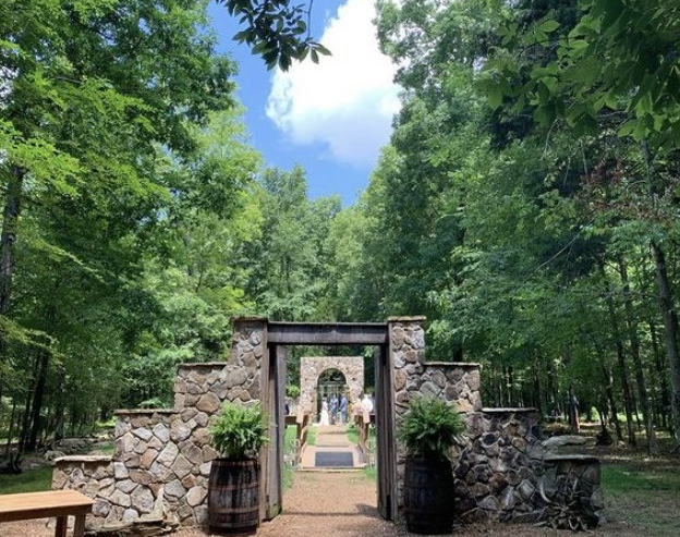 A stone archway leading to a church in the middle of a forest.