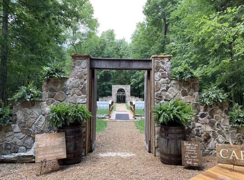 A stone archway leading to a stone building in the middle of a forest.