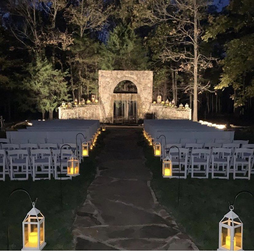 A row of white chairs are lined up in front of a stone building