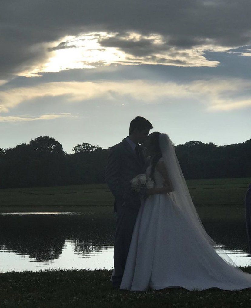 A bride and groom kissing in front of a lake