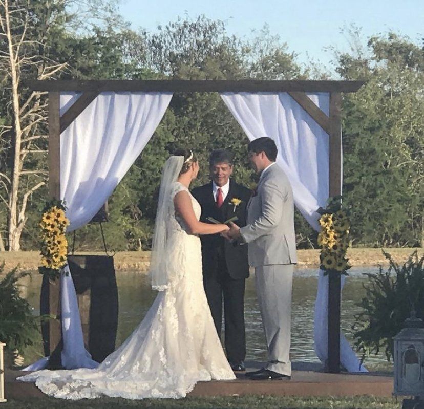 A bride and groom are holding hands during their wedding ceremony