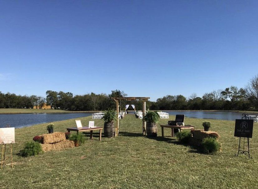 A wedding ceremony is taking place in a field with a lake in the background.