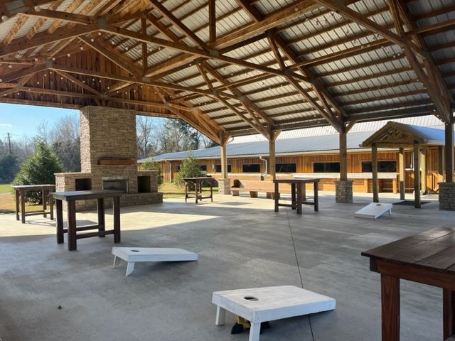 A covered area with cornhole bags and tables under a roof