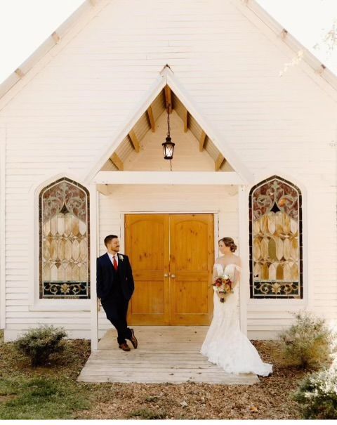 A bride and groom standing in front of a church