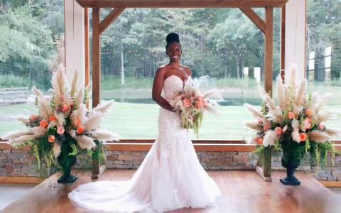A bride in a wedding dress is standing in front of a window holding a bouquet of flowers.