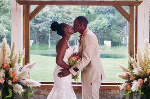 A bride and groom are kissing in front of a window.
