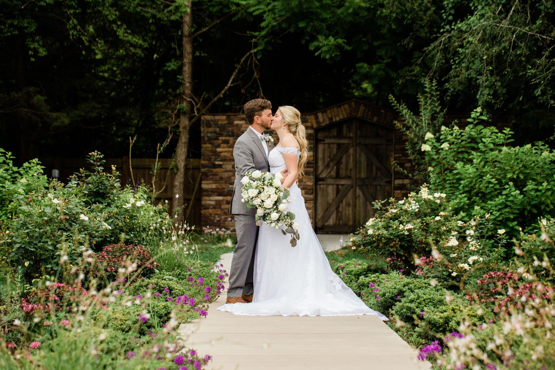 A bride and groom are kissing in a garden.