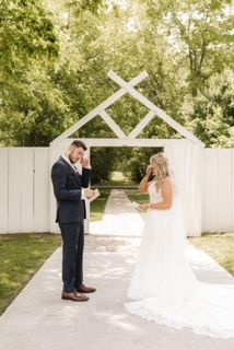 A bride and groom are standing next to each other in front of a white building.