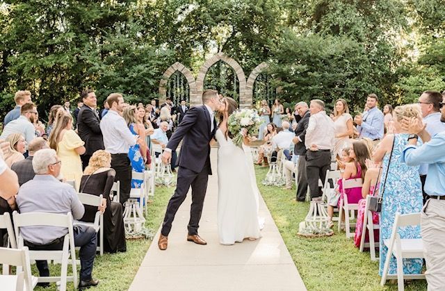 A bride and groom kissing at their wedding ceremony in front of their wedding guests.