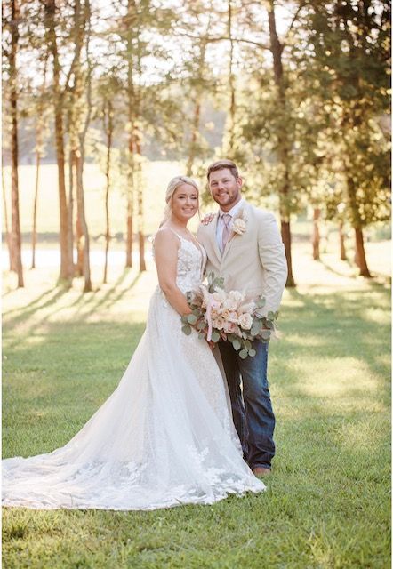 A bride and groom are posing for a picture in the grass.