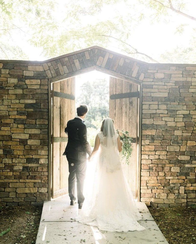A bride and groom are walking through a doorway holding hands.