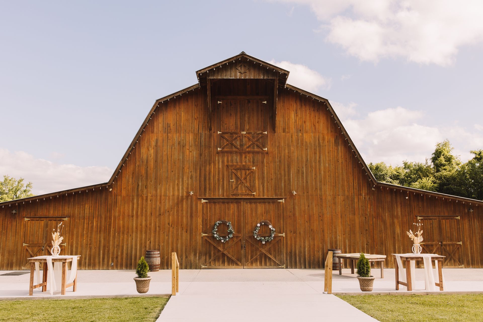 A large wooden barn with a concrete walkway leading to it.