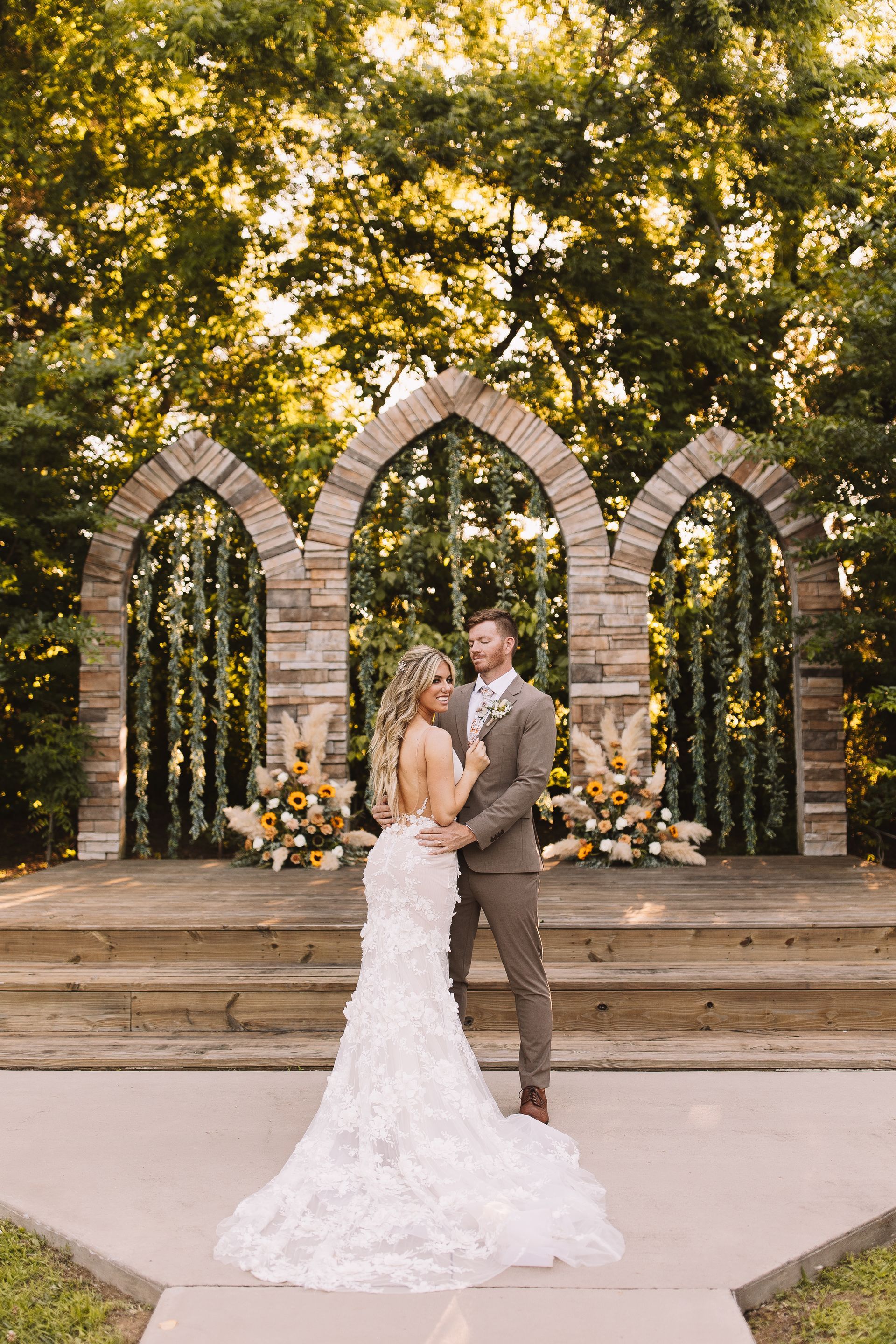 A bride and groom are posing for a picture in front of a stone archway.