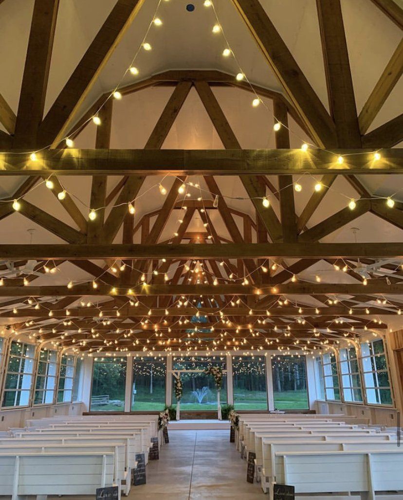 The inside of a church with rows of white benches and lights hanging from the ceiling