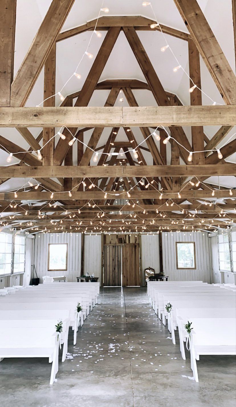 A church with white benches and lights hanging from the ceiling.