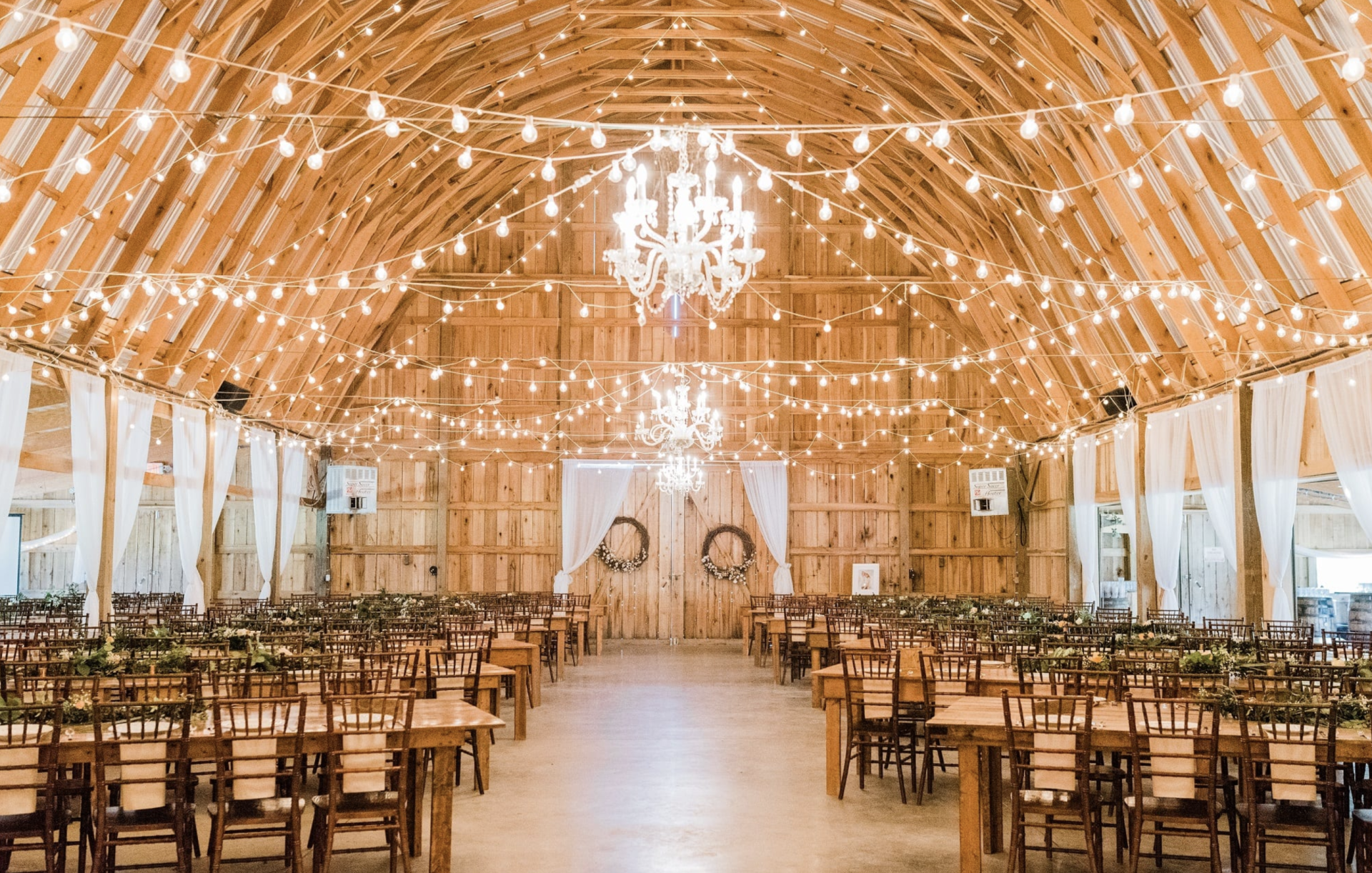 A large barn filled with tables and chairs for a wedding reception.