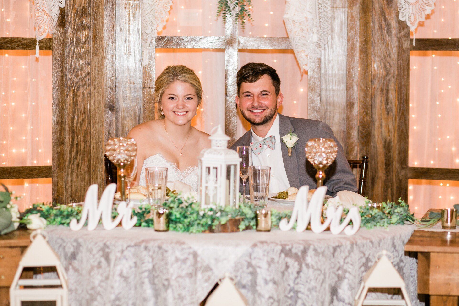 A bride and groom are sitting at a table at their wedding reception.