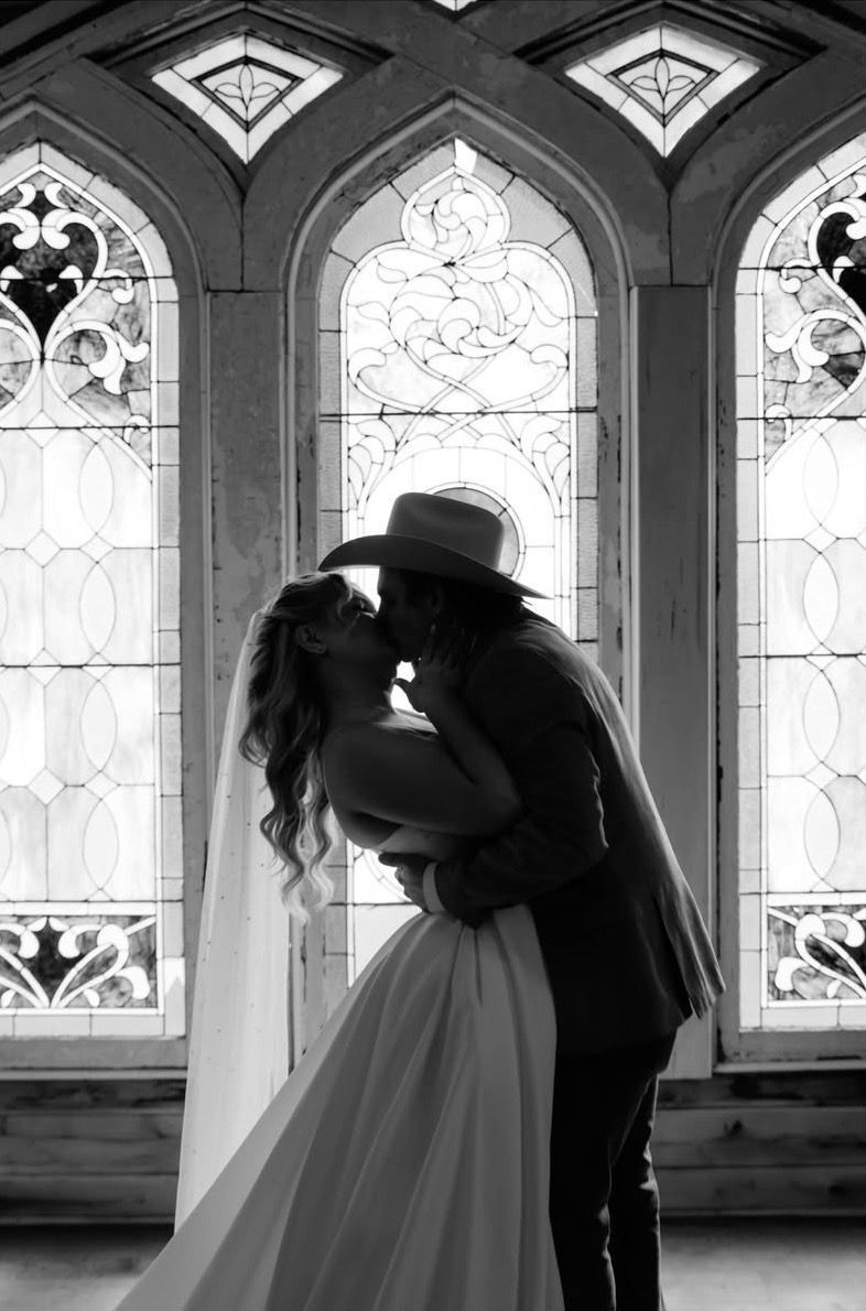 Couple embracing in silhouette before tall stained-glass windows