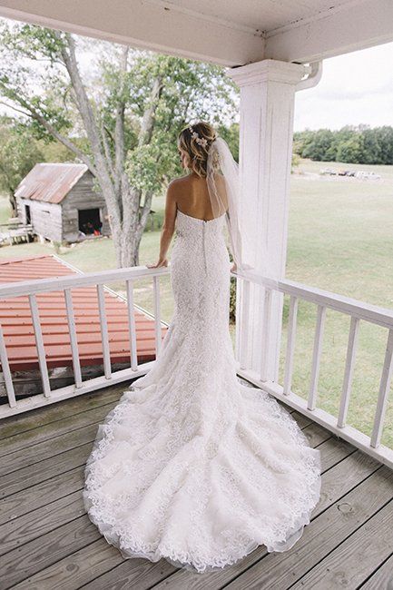 A bride in a wedding dress and veil is standing on a porch.