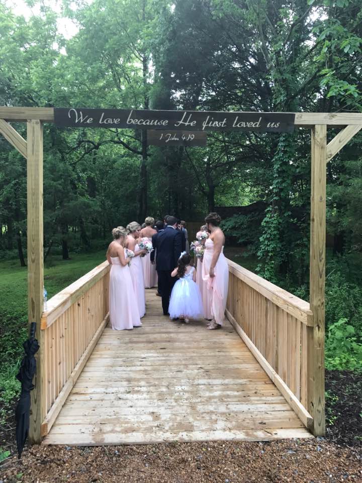 A group of people are walking across a wooden bridge.