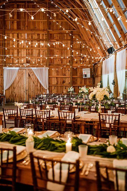 A barn filled with tables and chairs set up for a wedding reception.