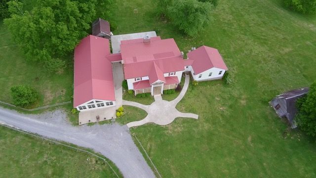 An aerial view of a large house with a red roof surrounded by trees