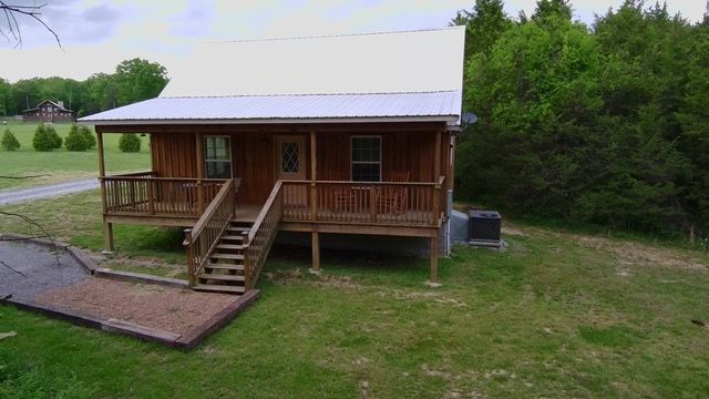 An aerial view of a small wooden house with a porch and stairs
