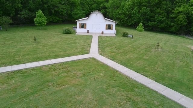An aerial view of a small white church in the middle of a lush green field