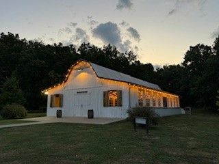 A white barn is lit up at night with lights on the roof