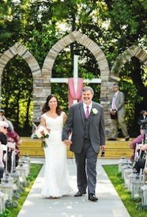 A bride and groom are walking down the aisle at their wedding holding hands.