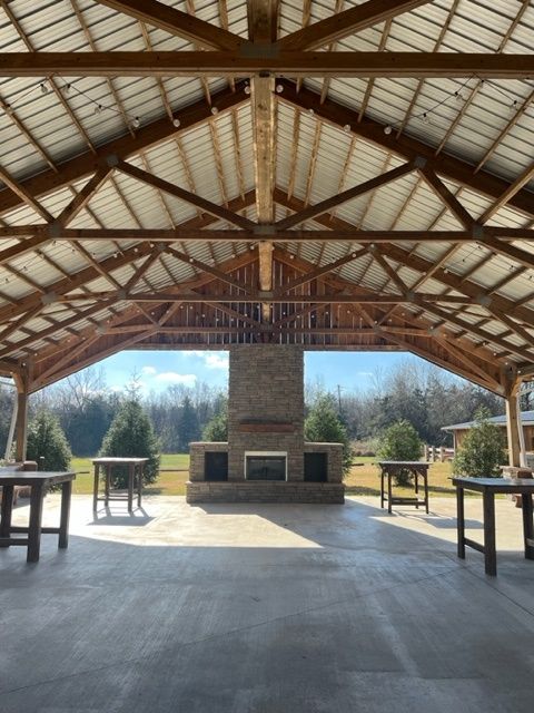 The inside of a pavilion with tables and a fireplace.