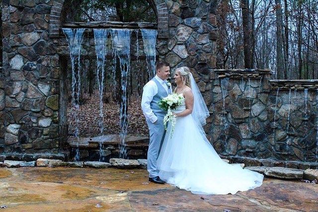 A bride and groom are posing for a picture in front of a waterfall.