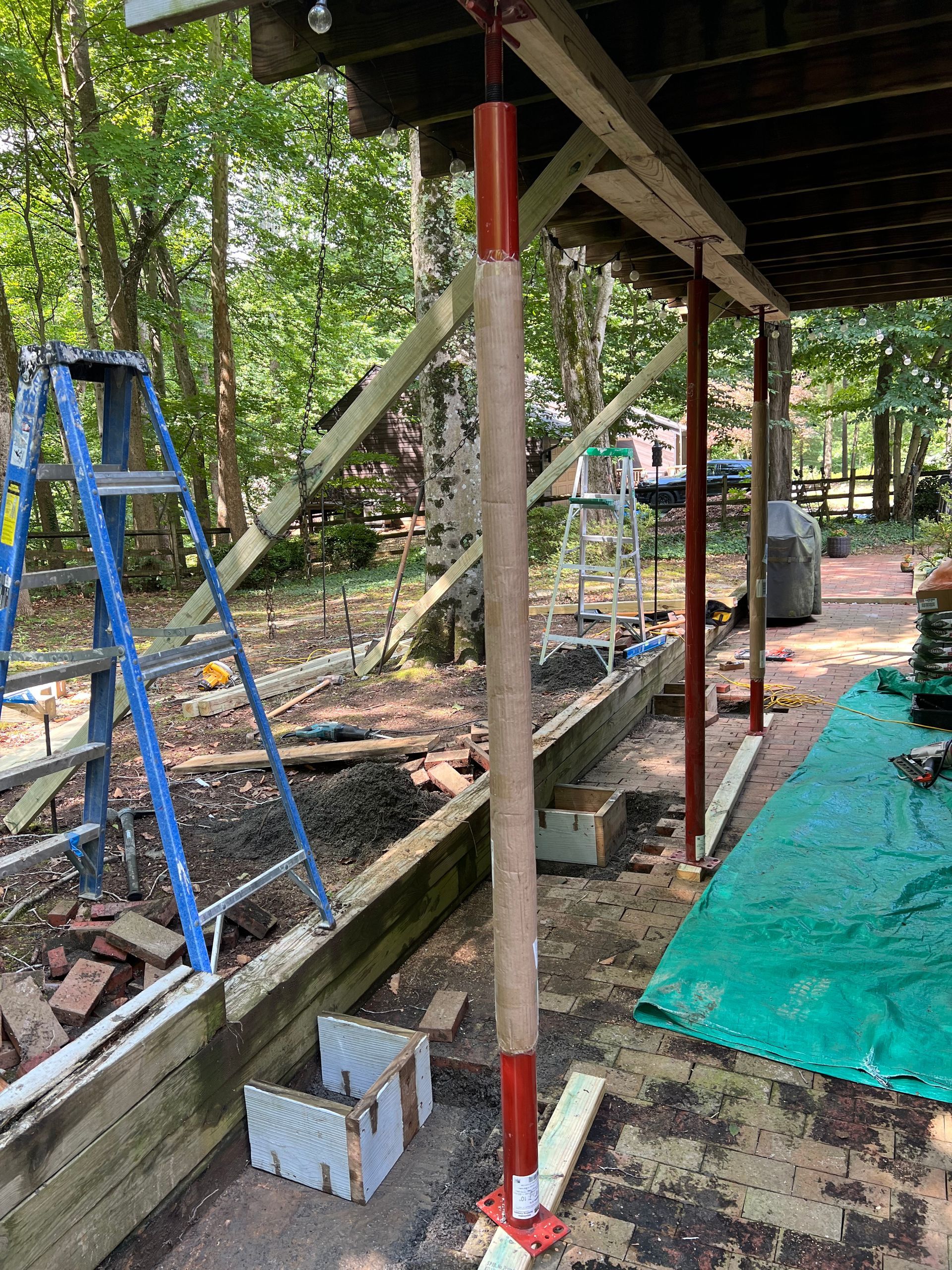 A wooden structure is being built in the woods with a ladder in the background.