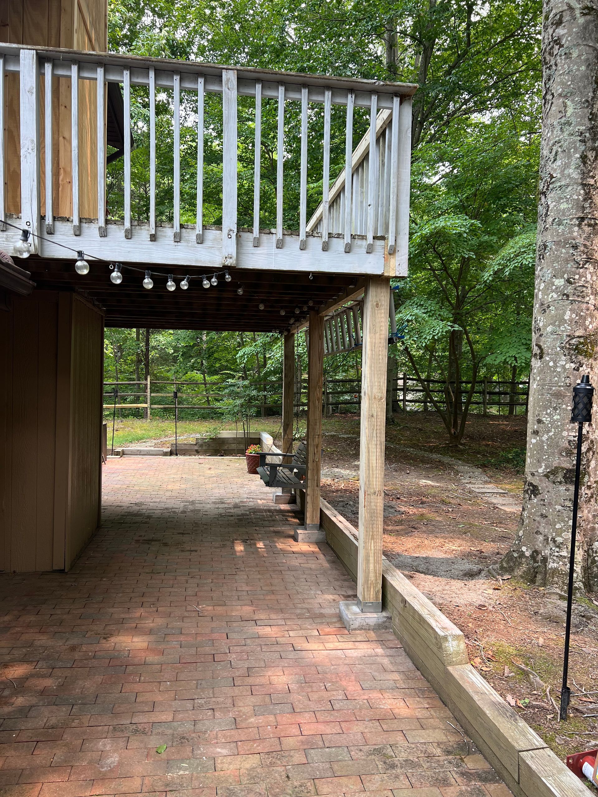A brick walkway leading to a deck in the woods.