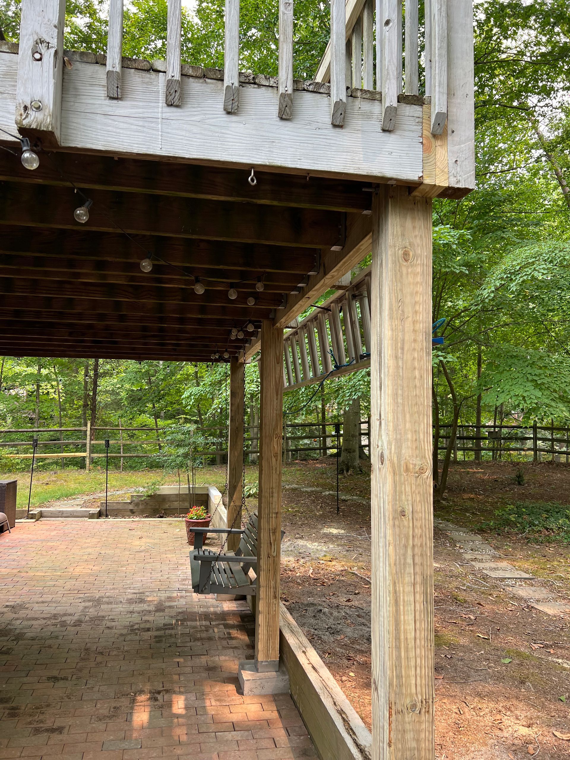 A wooden deck with a covered area underneath it in the woods.