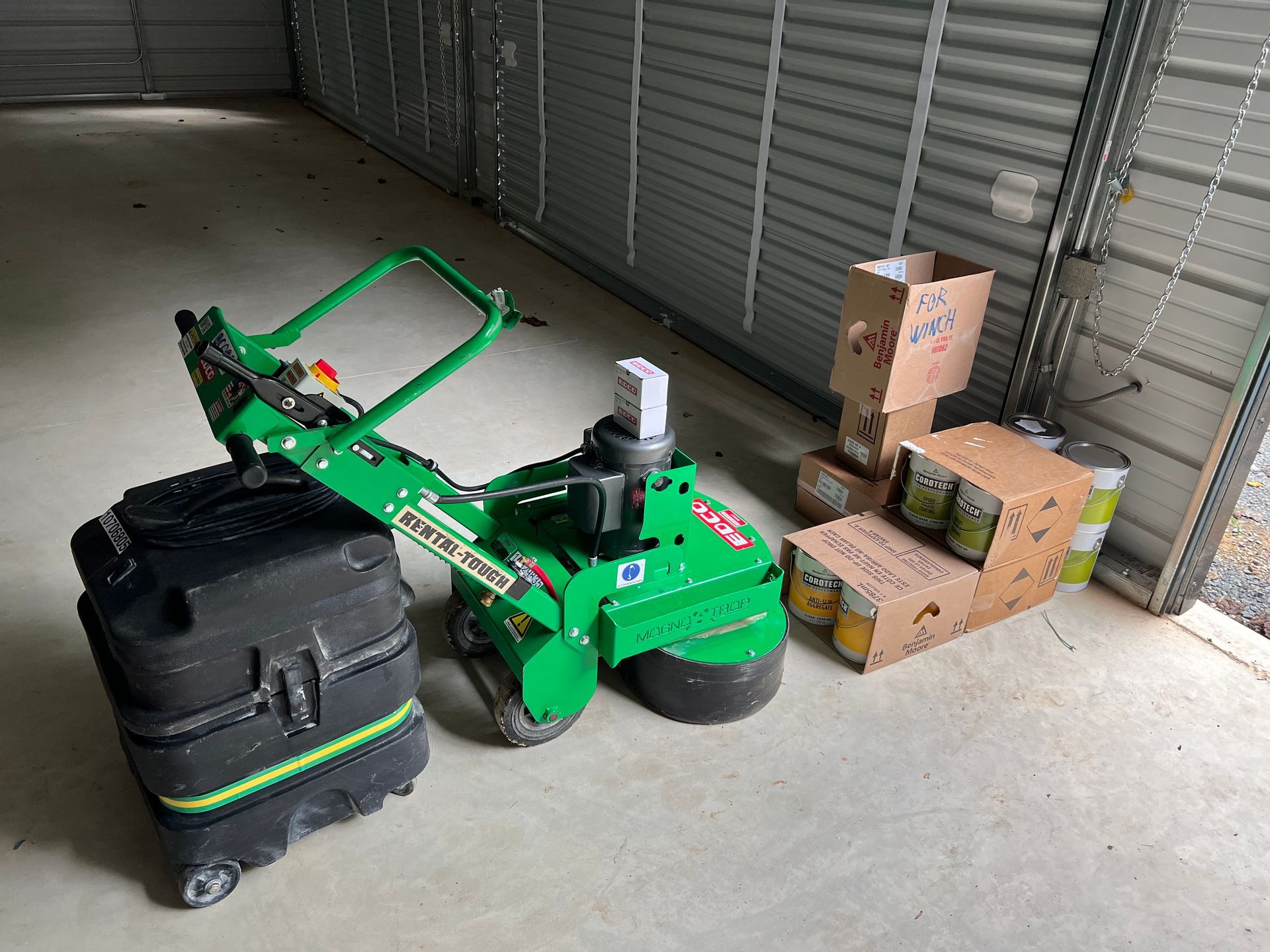 A green machine is sitting in a garage next to boxes.