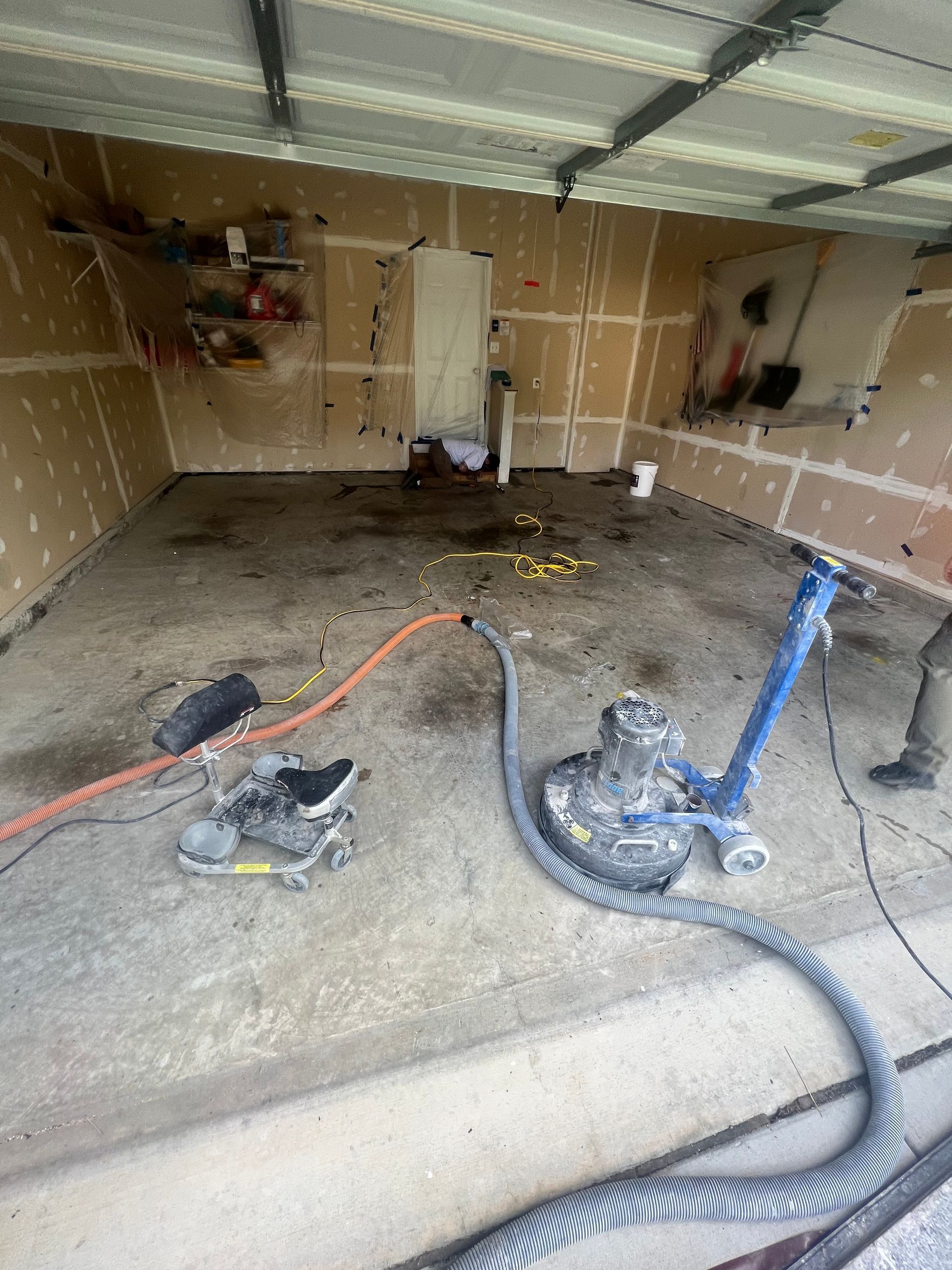 A garage with a vacuum cleaner and a grinder on the floor.