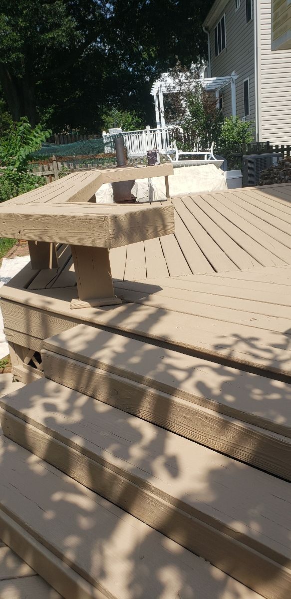 A wooden deck with a table and stairs in front of a house.