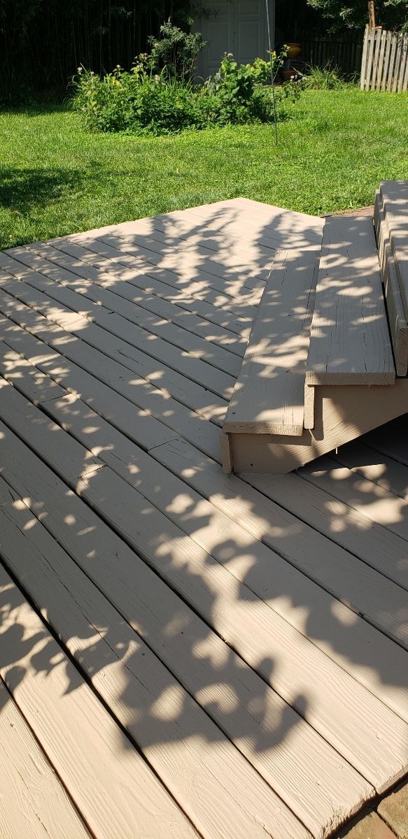 A wooden deck with stairs and a shadow of a tree on it.