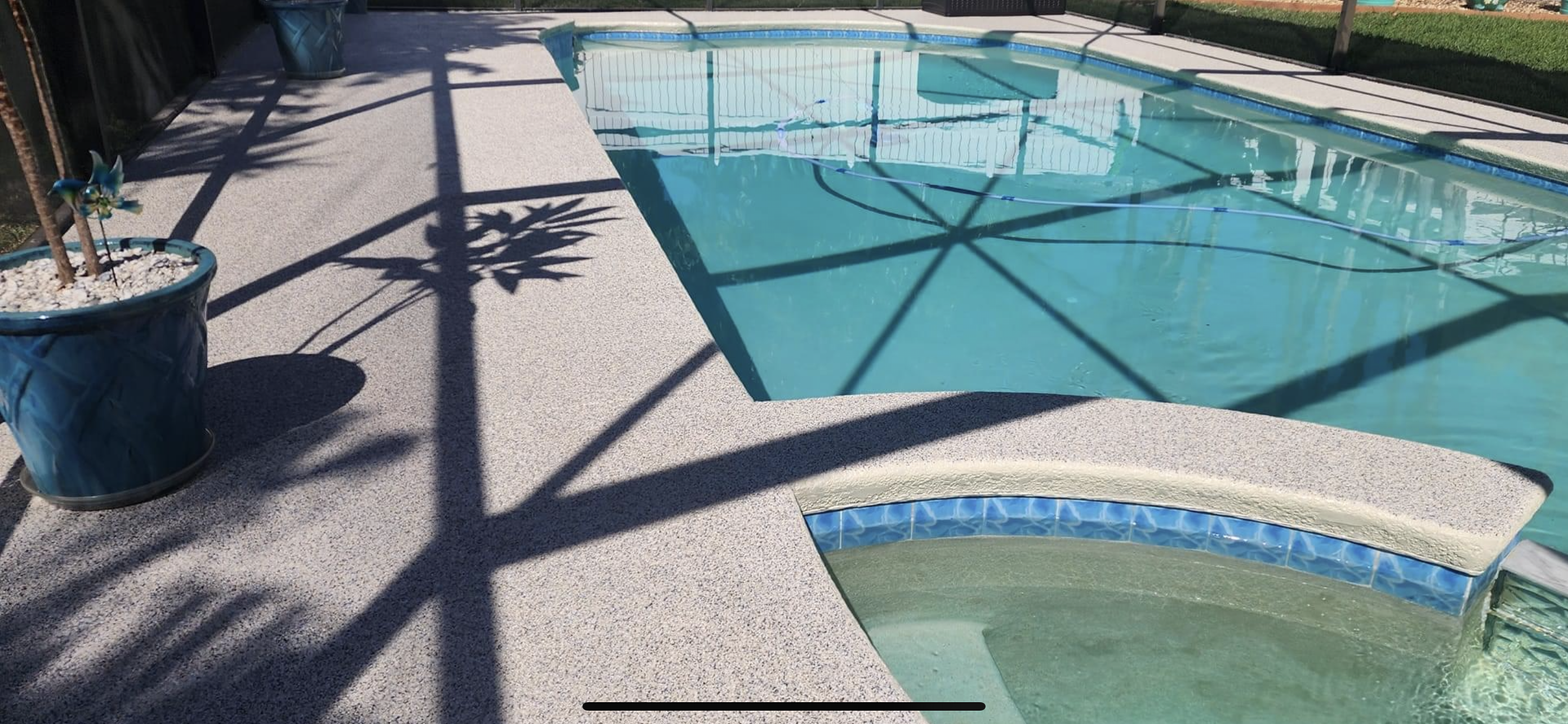 A large swimming pool with a hot tub next to it.