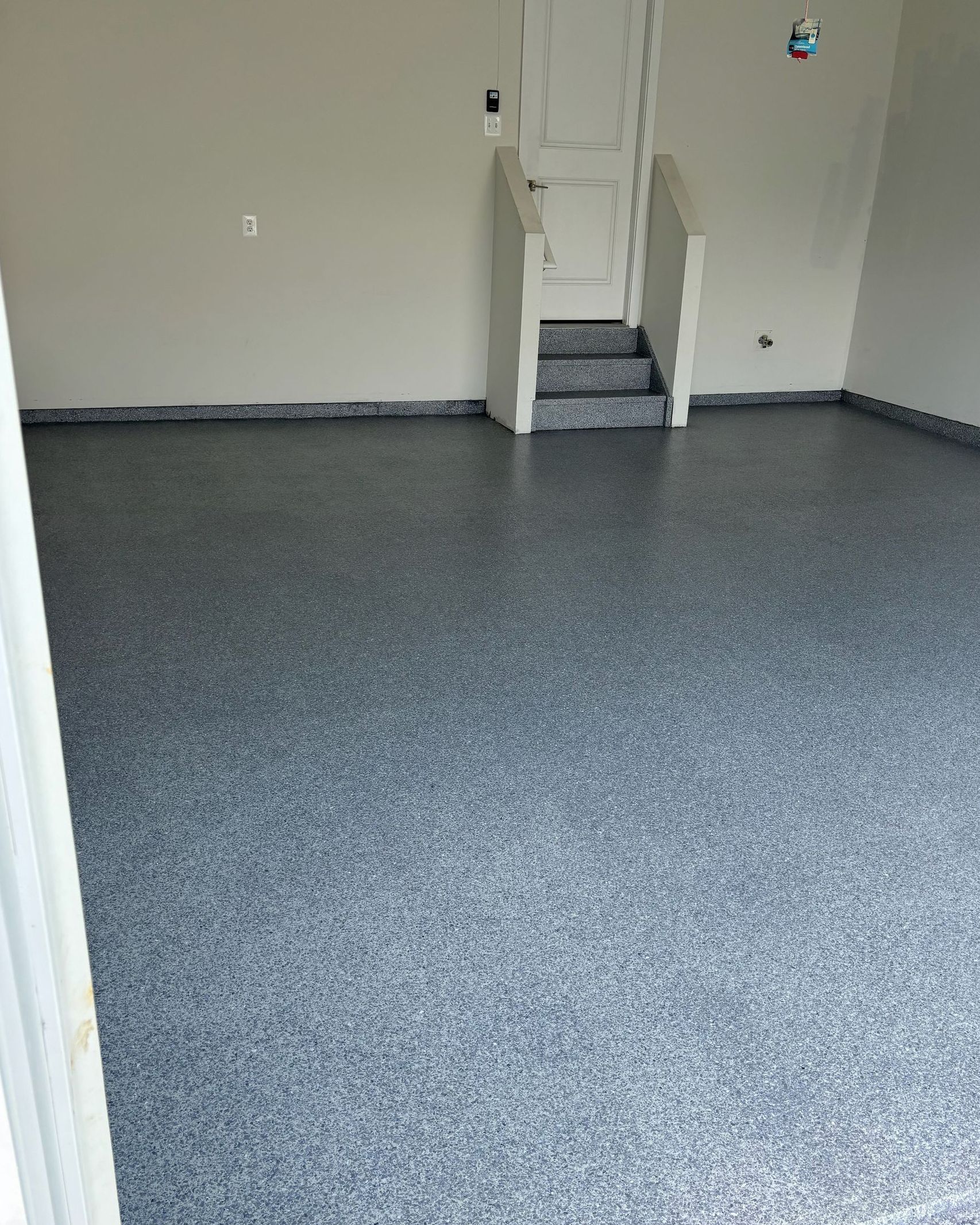 A garage with a staircase and a gray floor.