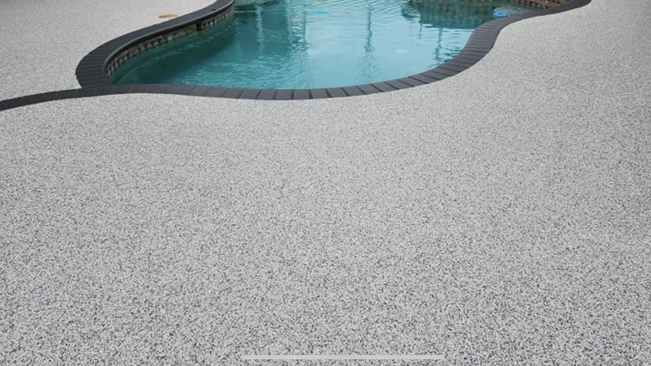 A swimming pool with a concrete floor next to it.