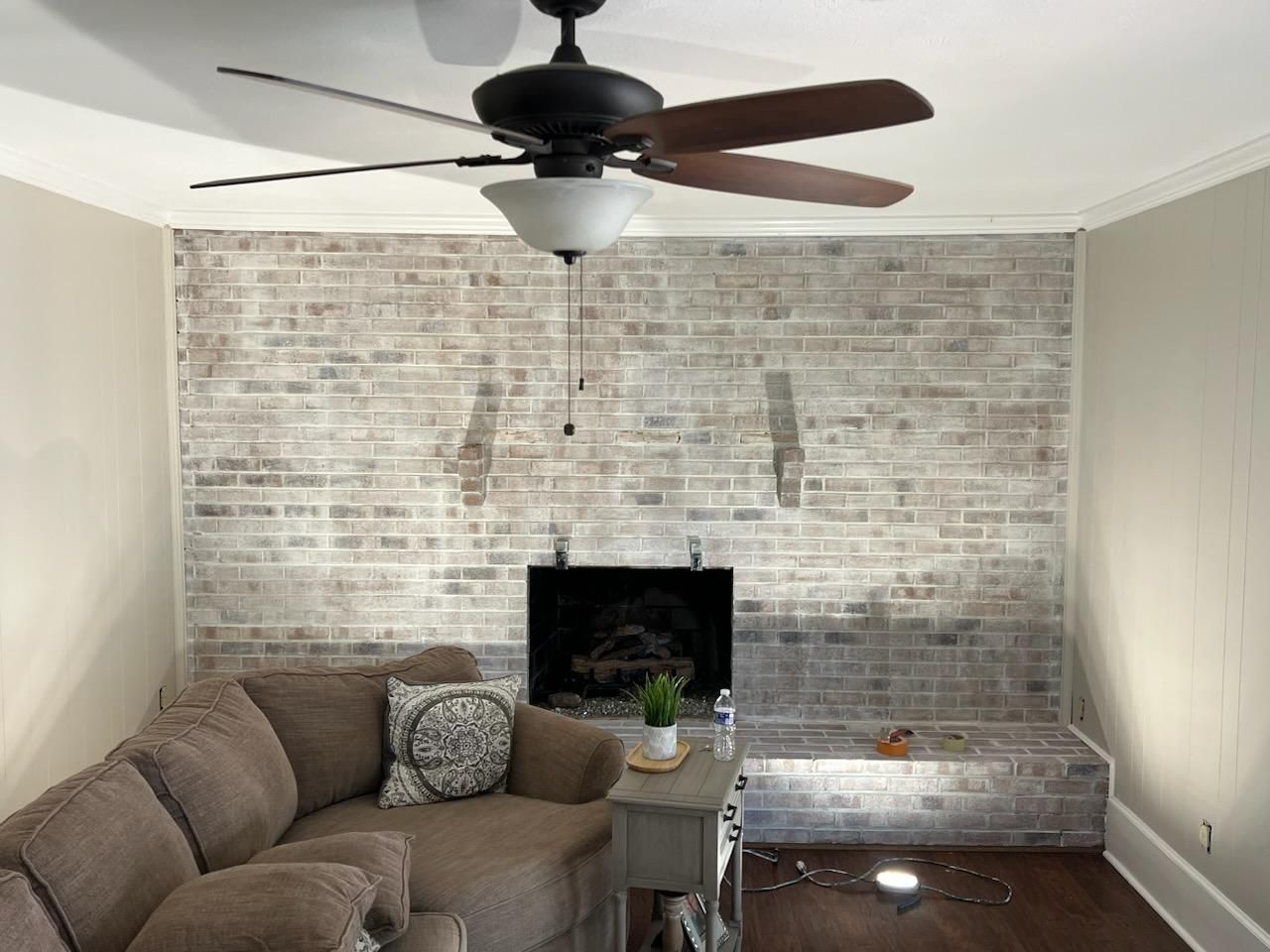 A living room with a fireplace and a ceiling fan after painting job