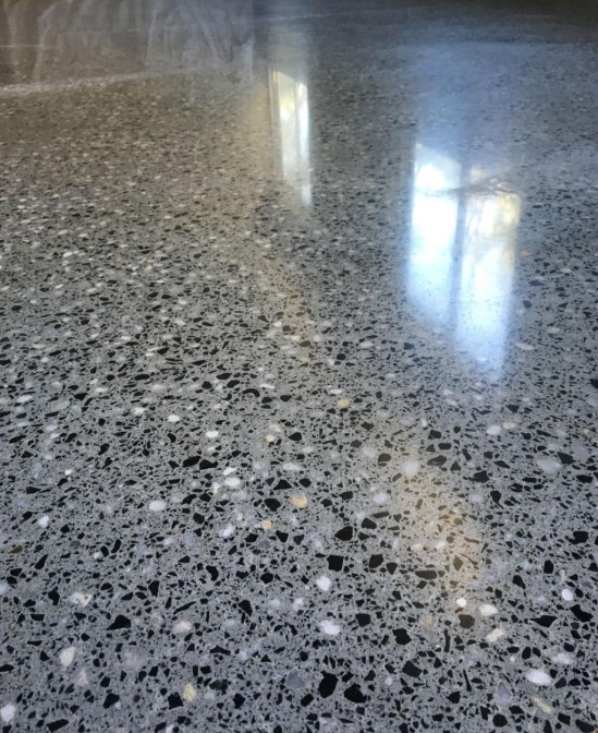 A close up of a shiny concrete floor with black and white stones.