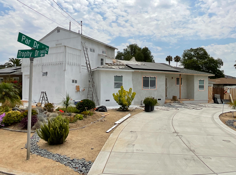 White house at a curved driveway corner with desert landscaping and green street signs.