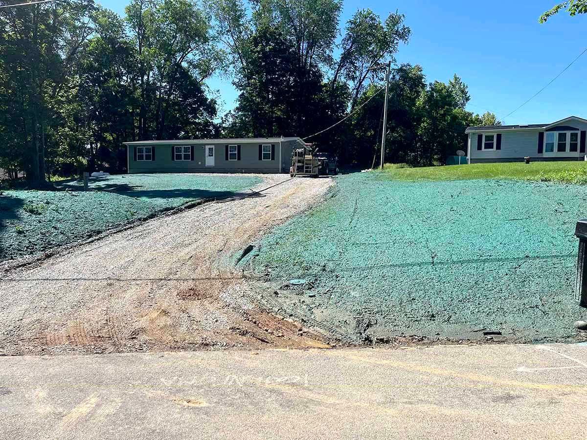 A driveway with a wide lawn under hydroseeding process