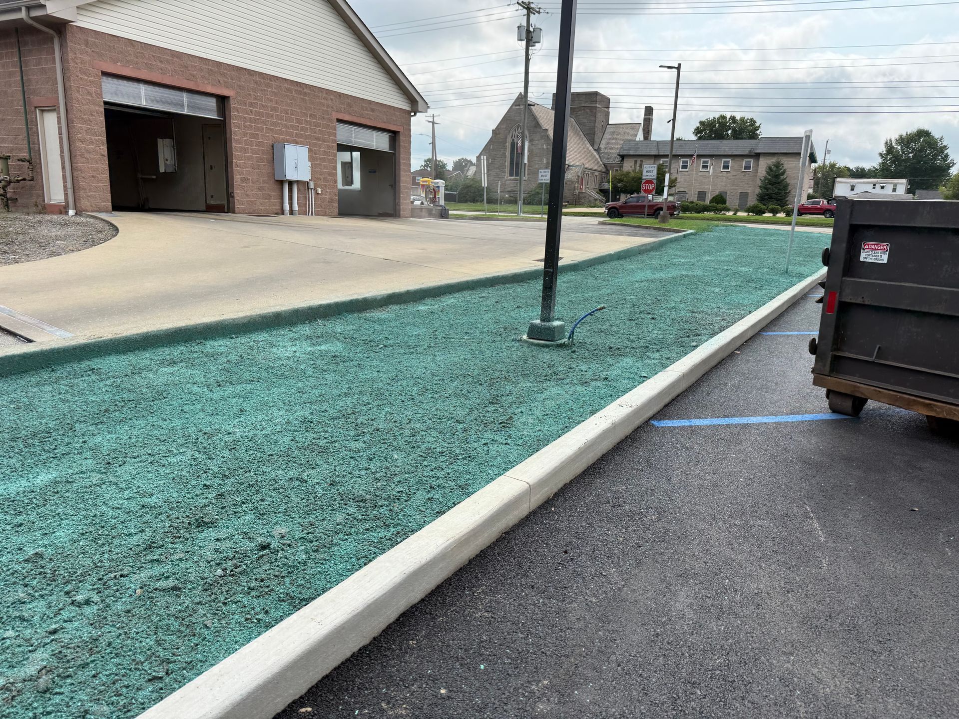 Newly landscaped strip of green ground cover beside a brick building and parking lot