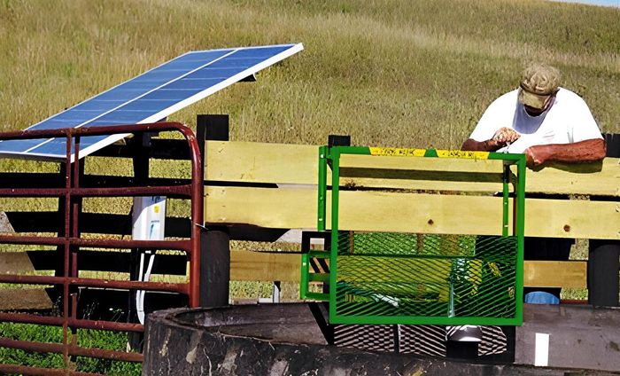 A man sitting on a wooden fence with a solar panel in the background