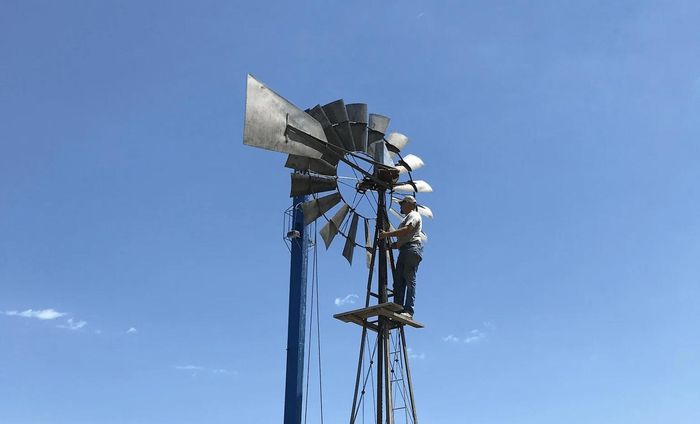 A large windmill is against a blue sky.