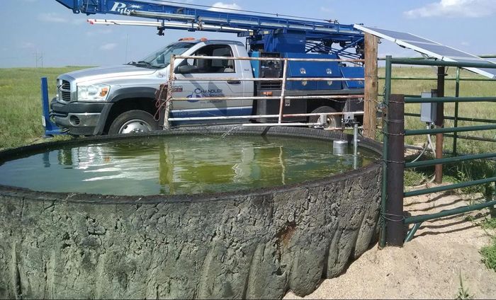 A truck is parked next to a large tank of water